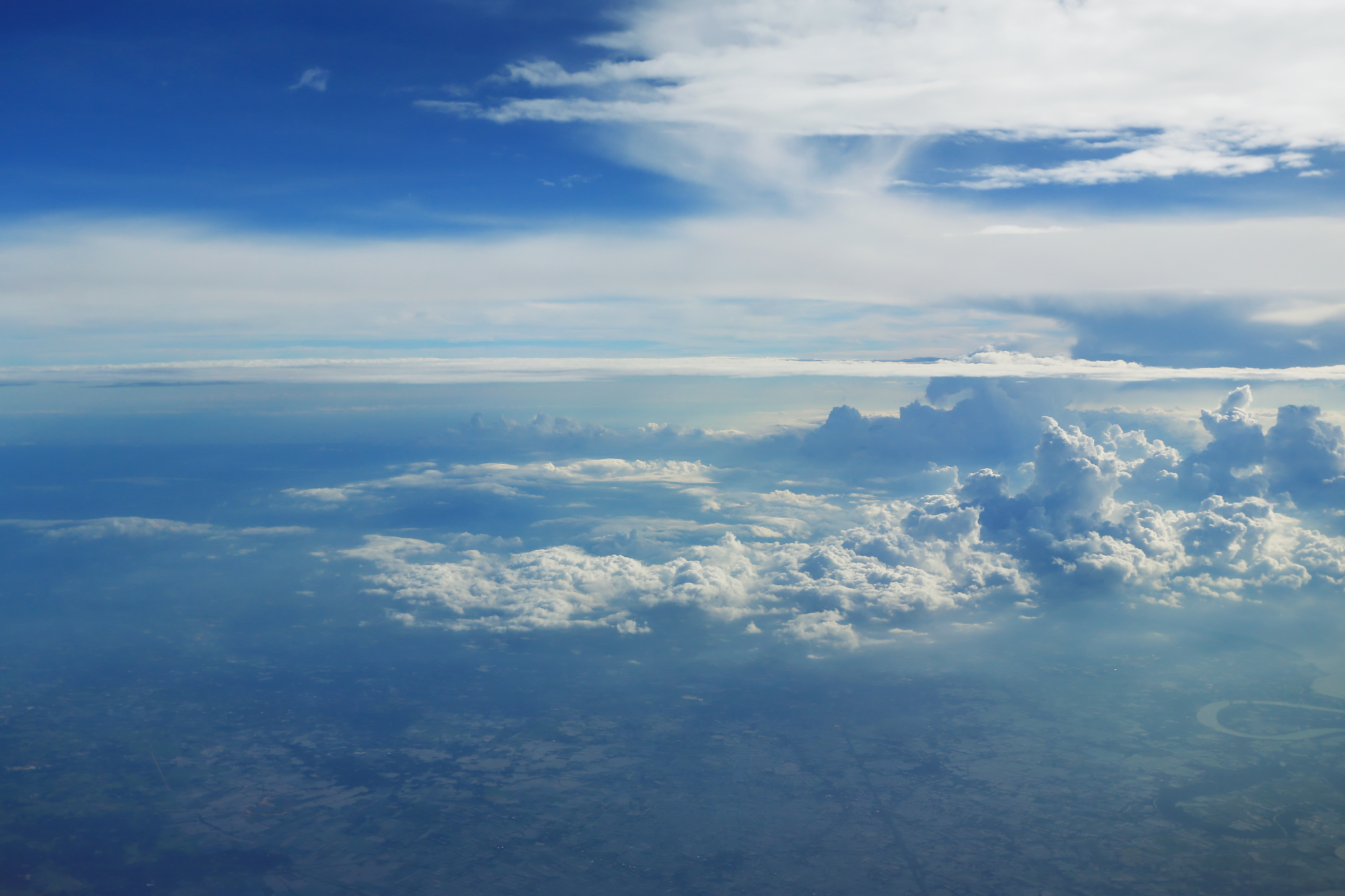 View from the aeroplane above the clouds towards the sky, the earth can be seen in the distance