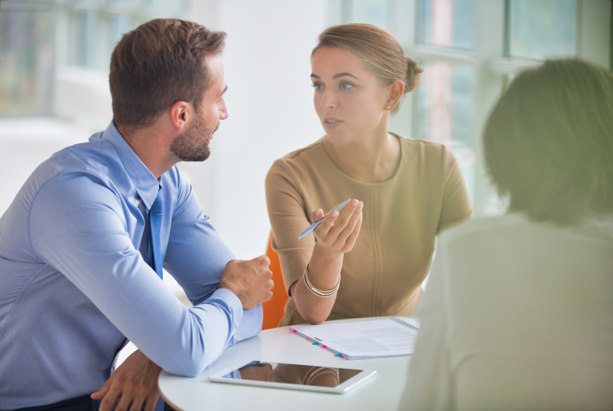Young colleagues discussing over document at table during meeting