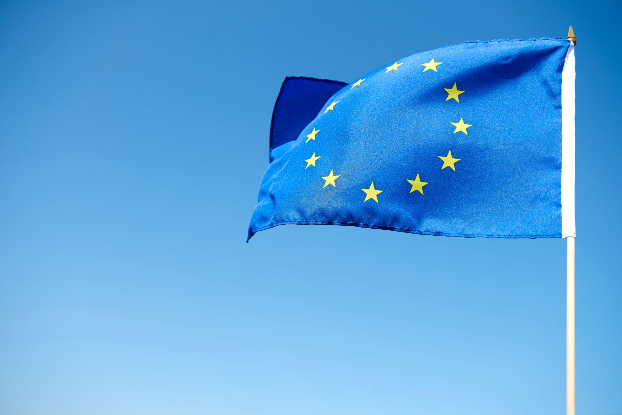 EU flag is blowing in the wind in front of a cloudless sky