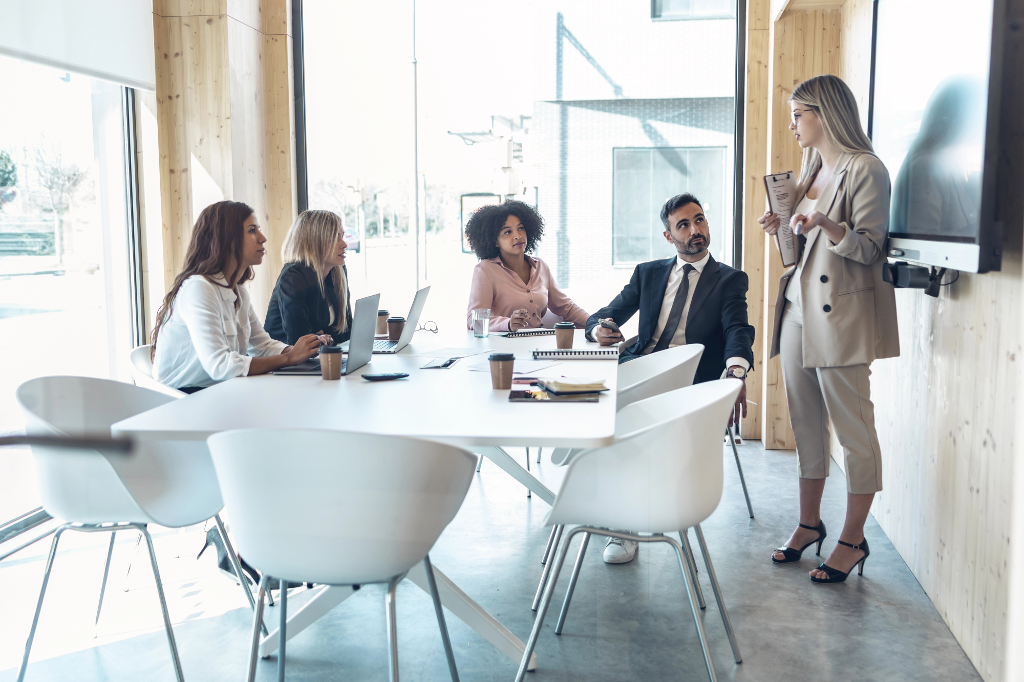 Female entrepreneur explaining to multi-ethnic coworkers in office