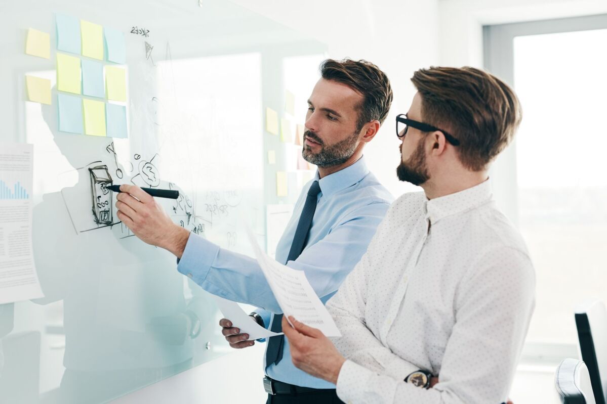 kvp-dqs-zwei maenner arbeiten zusammen an flipchart mit stiften und notizzetteln