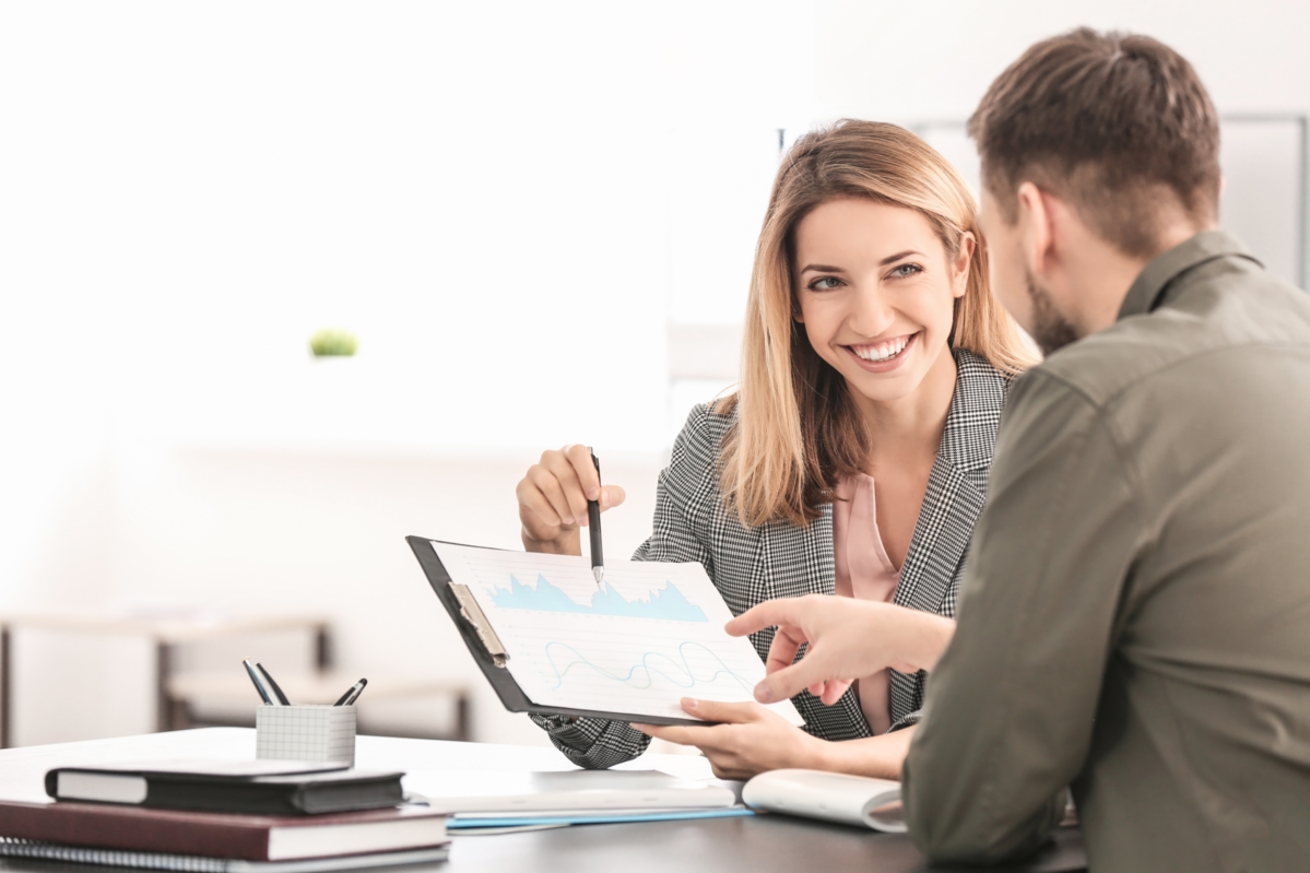 dstv-quality-seal-dqs-a blond young woman at a desk points with a pen at a clipboard with a graphic 