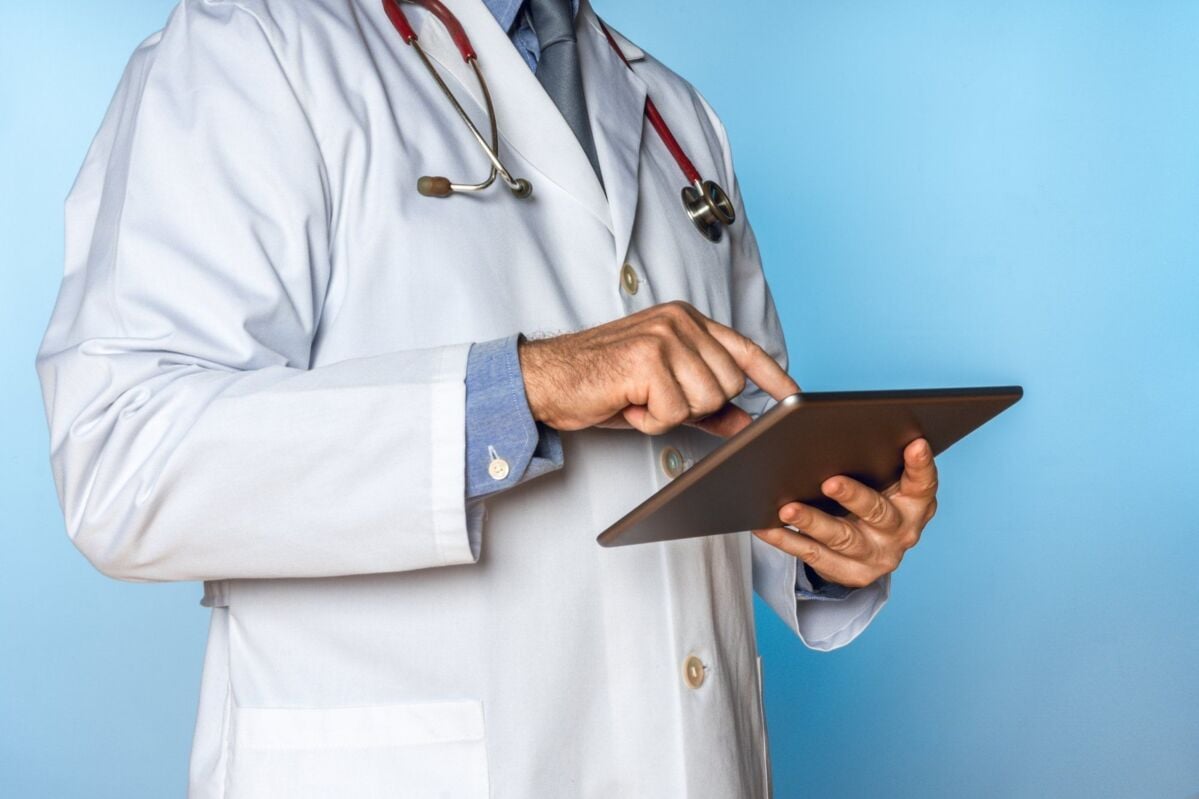 unrecognizable doctor working with a tablet on a blue background