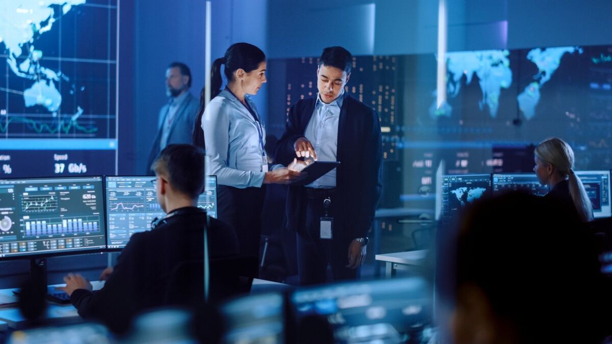 new-iso-iec-27001-2022-blog-dqs-project managers converse when using a tablet in a central room