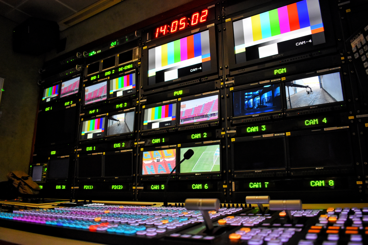 Equipment in a television broadcast van with monitor wall, control desks and microphone