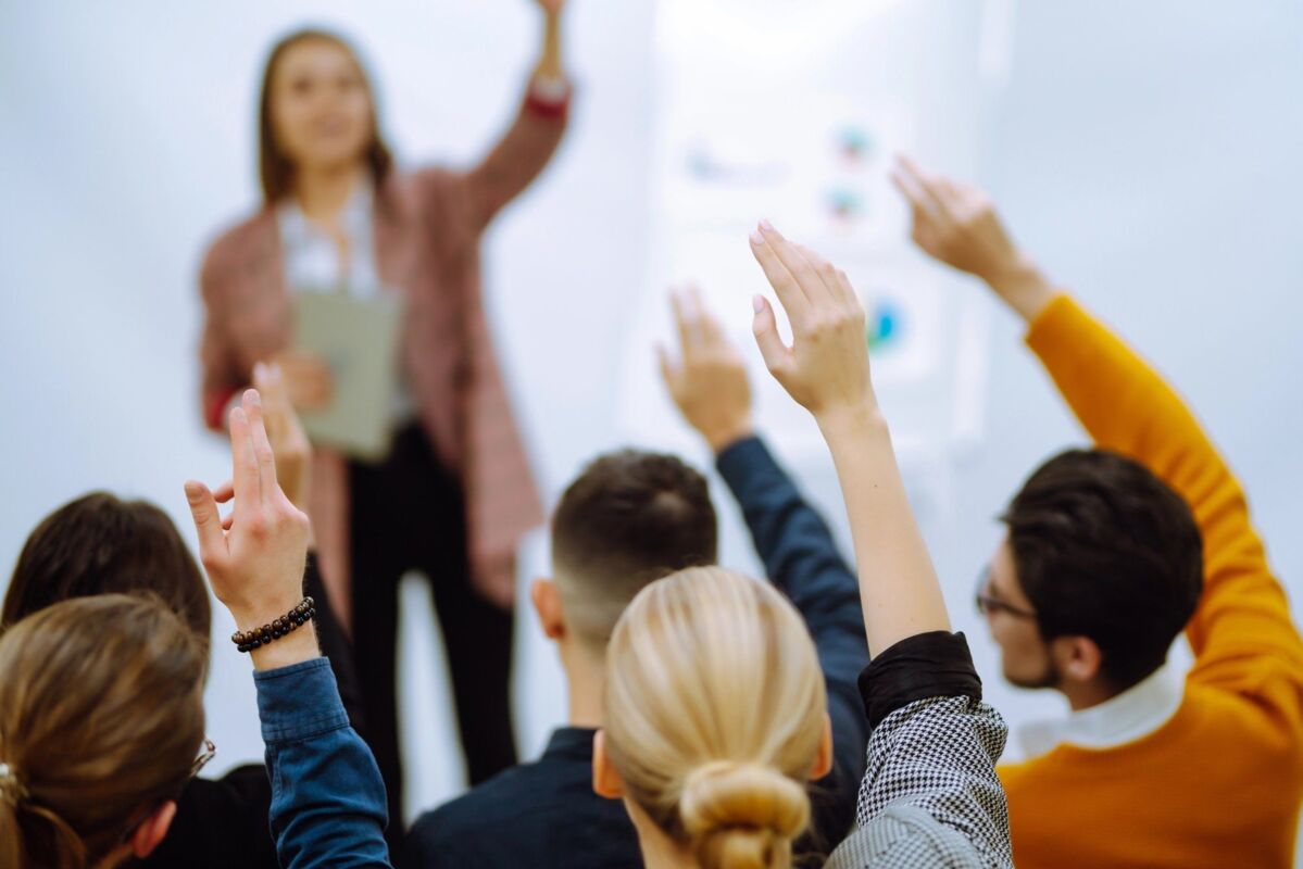 Many people raising their hands to answer during a seminar or webinar