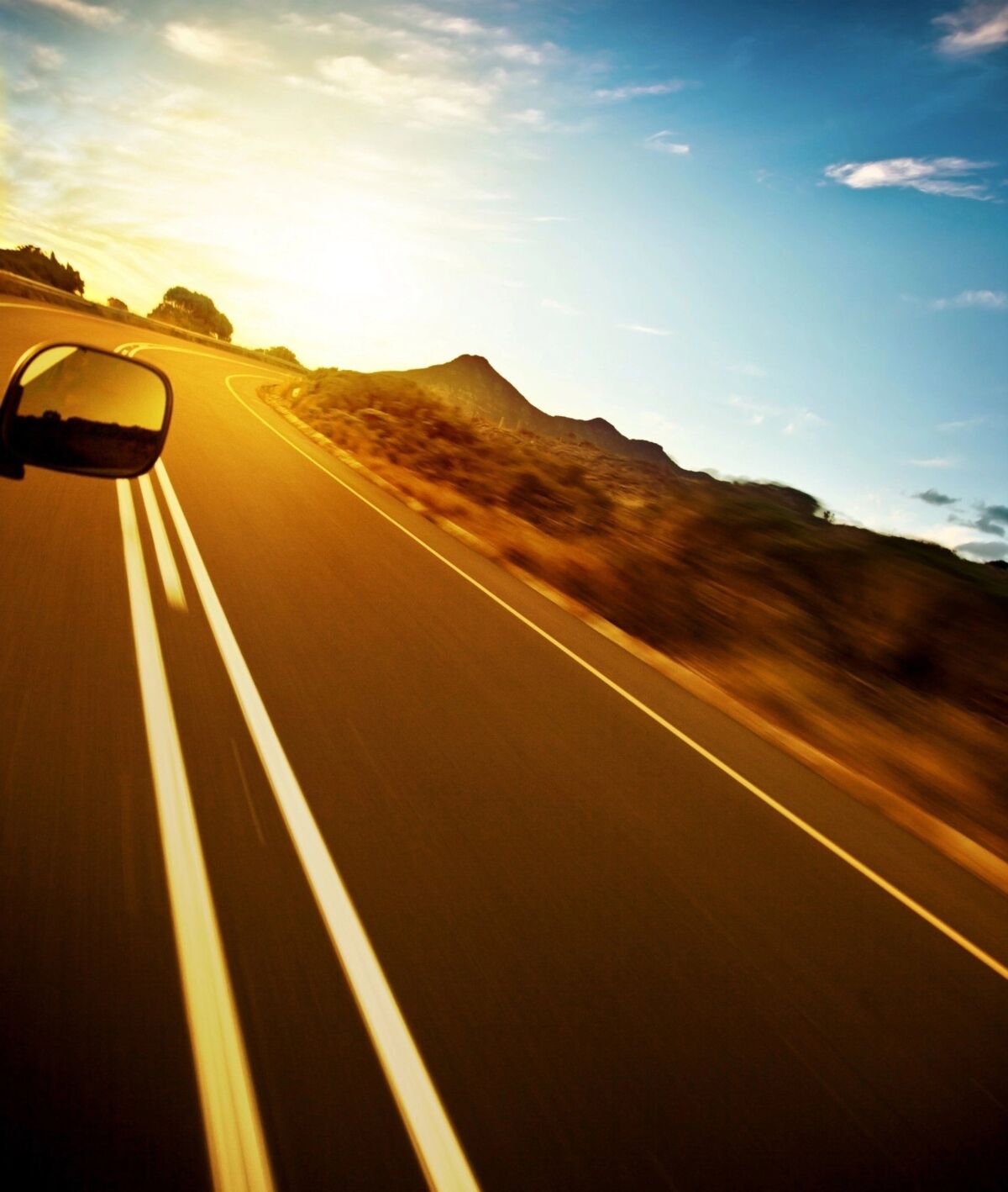 car travelling on a highway towards the mountains under blue sky