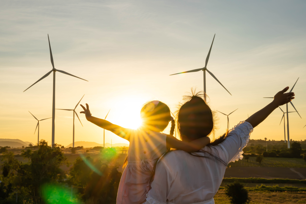 Mother and daughter looking at wind turbines during sunset, renewable energy, sustainability, wind p