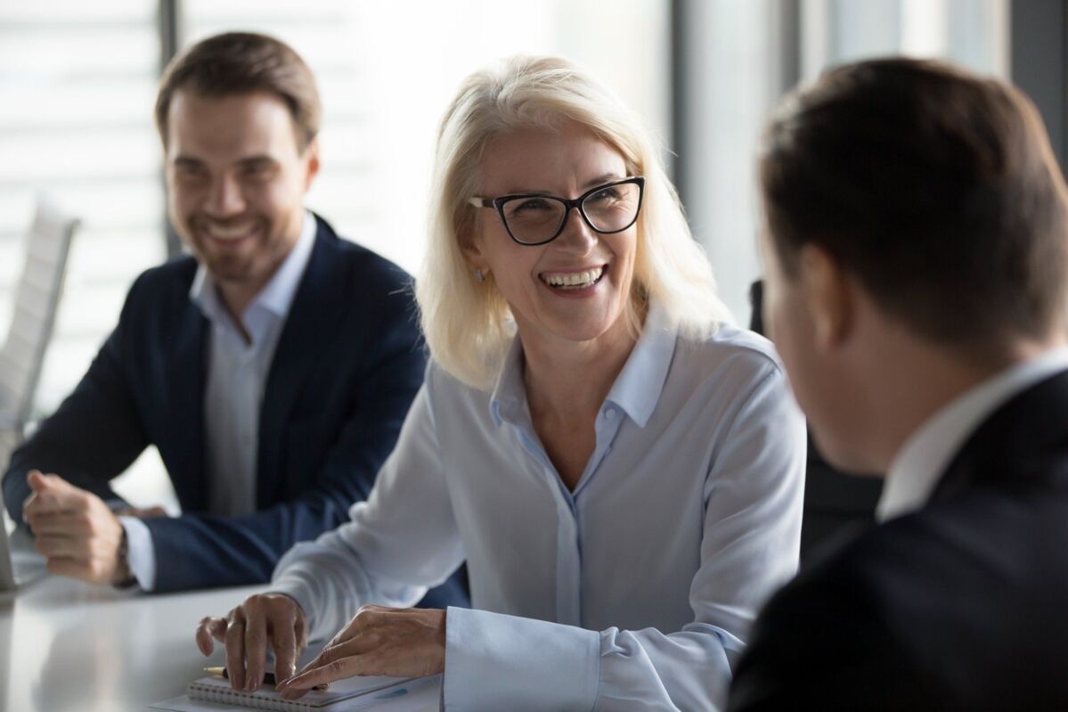 audit-dqs-three businessmen talking to a laughing woman with glasses in the foreground