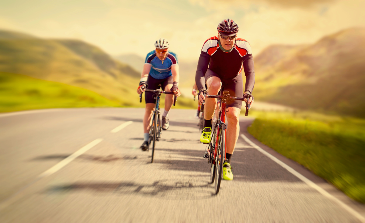 Two male cyclists riding uphill on a country road in the mountains.