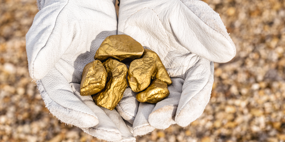Gloved hands holding minerals - gold