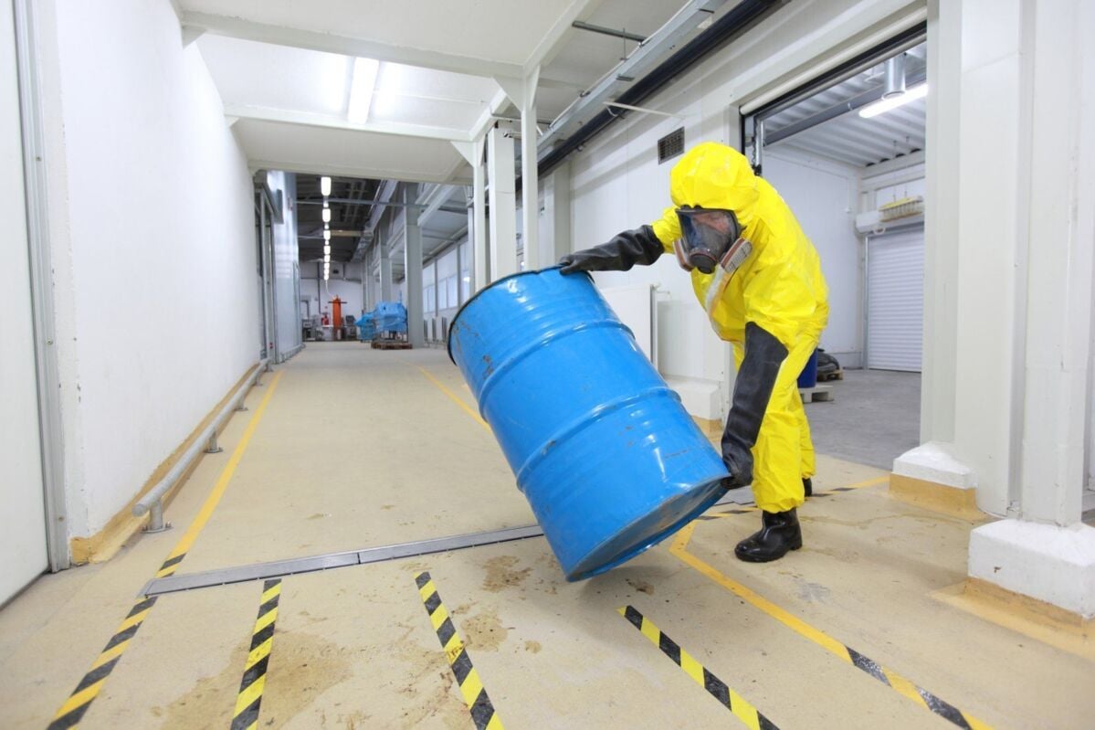 efbv-certification-dqs-a person in a yellow full-body protective suit rolls a light blue drum of spe