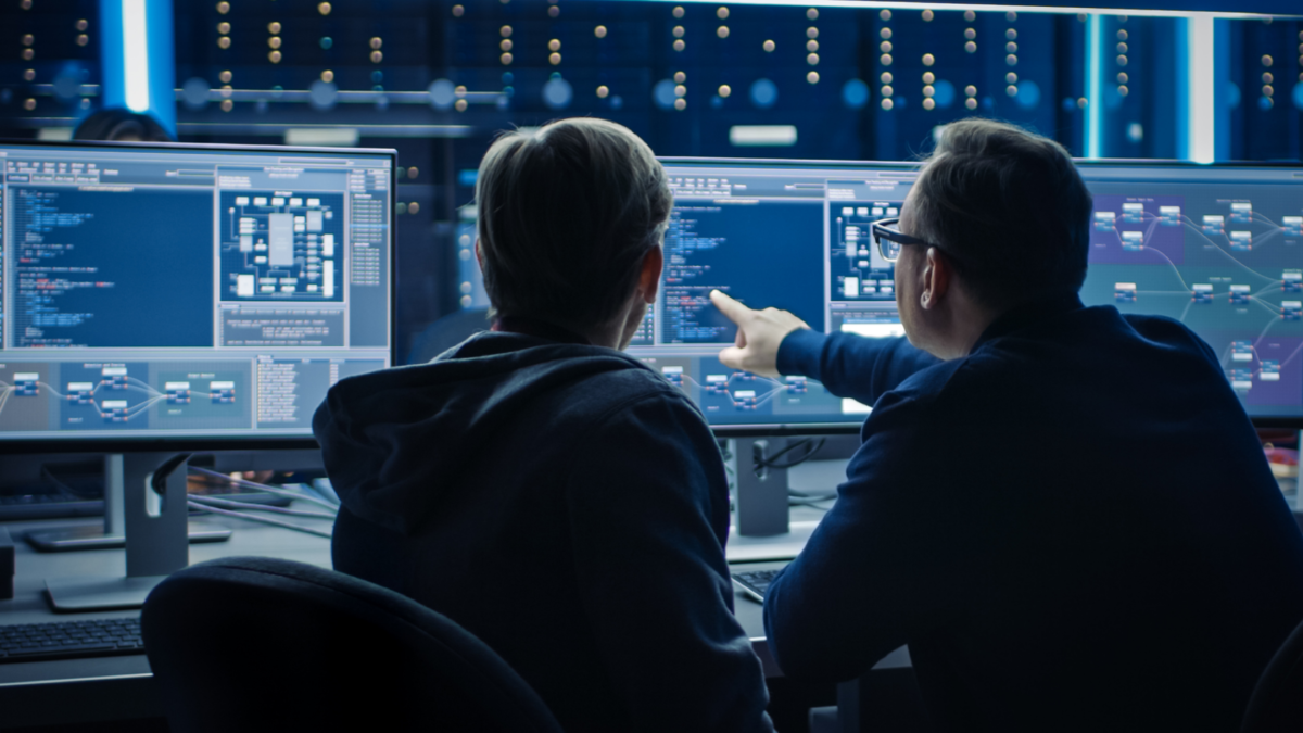 Two men are sitting in front of computers, looking at analyses.
