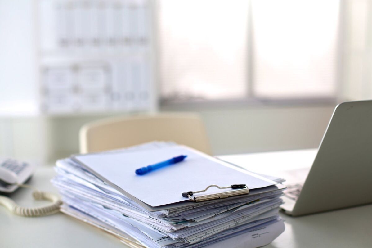 dqs-stack of papers next to laptop on desk