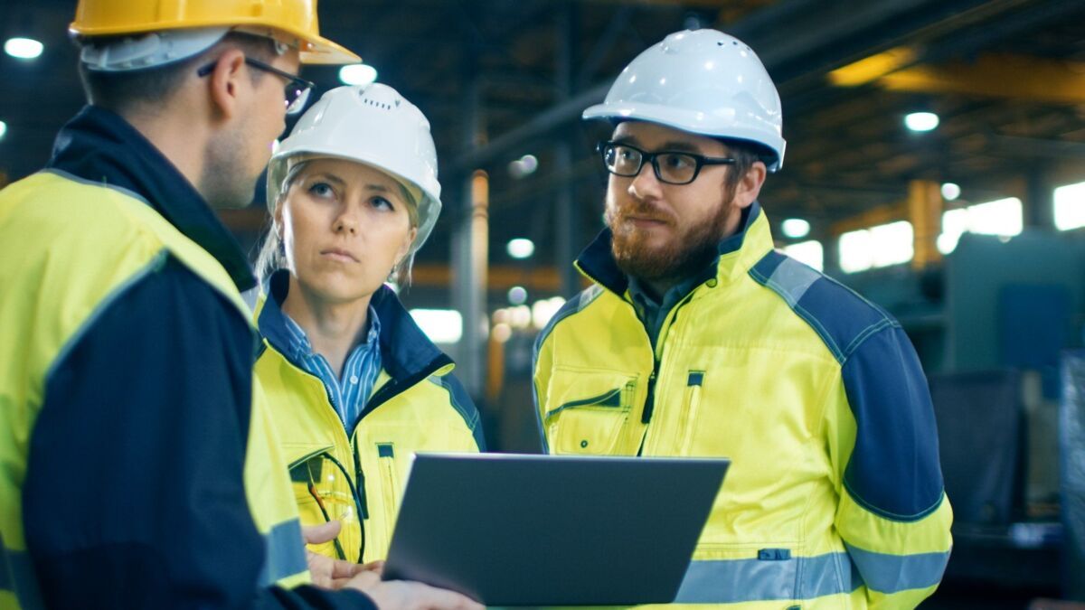 Male and Female Industrial Engineers Talk with Factory Worker while Using Laptop. They Work at the H