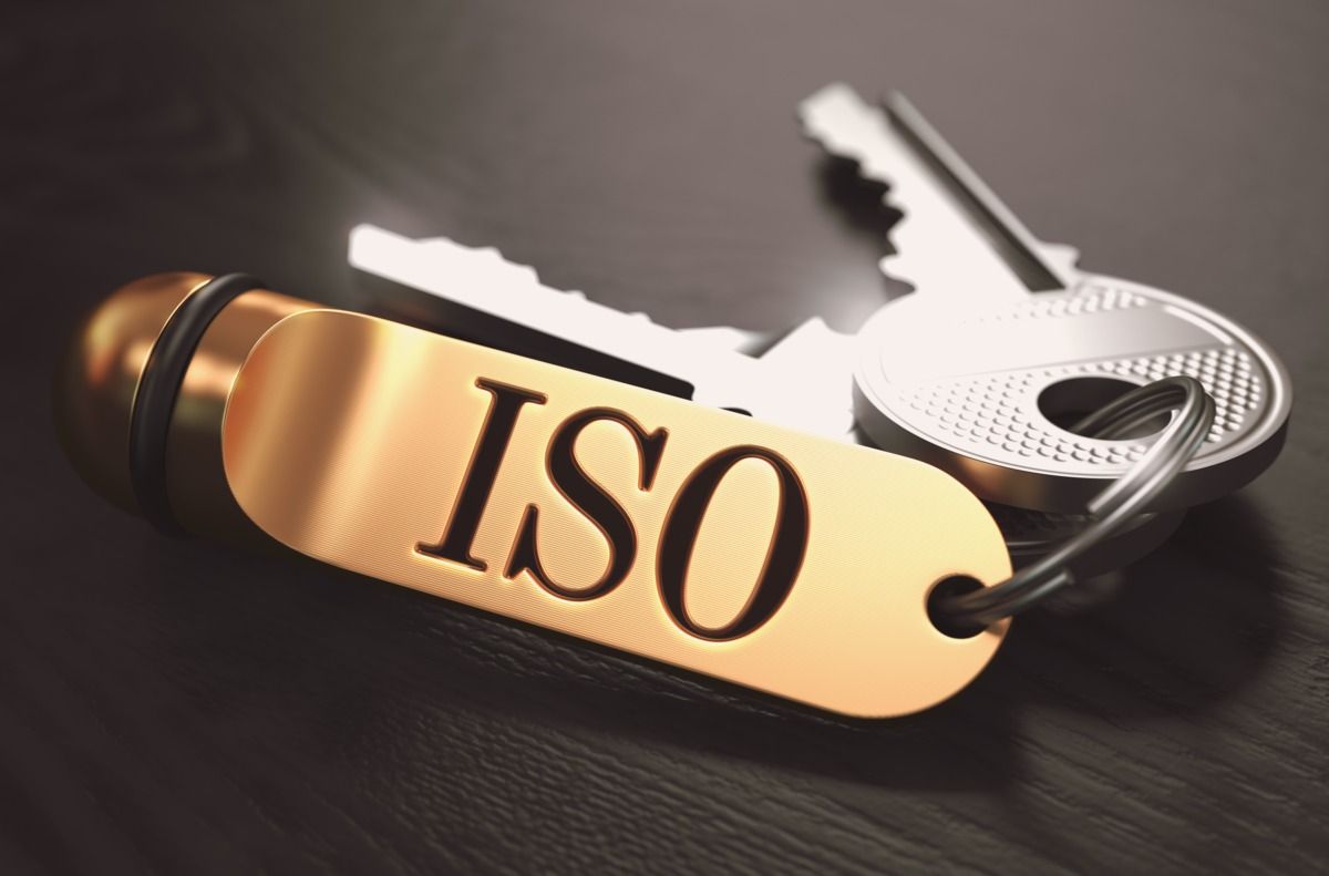 managementsystem-dqs-schluessel die auf holztisch liegen mit einem anhaenger auf dem iso steht