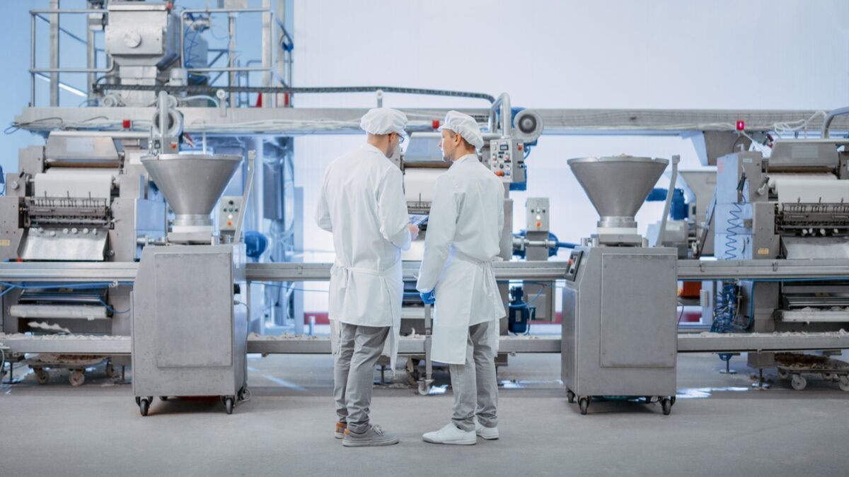 Two Young Food Factory Employees Discuss Work-Related Matters. Male Technician or Quality Manager Us