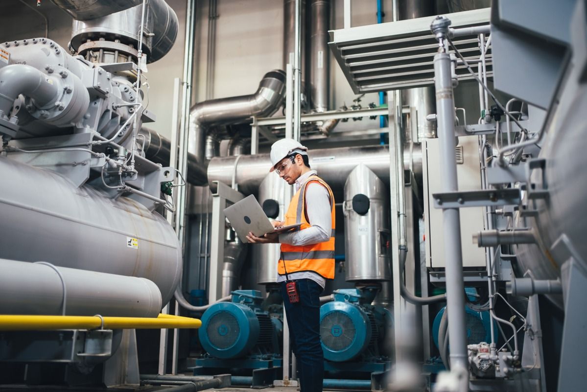 Man collecting energy data with a laptop in a manufacturing facility