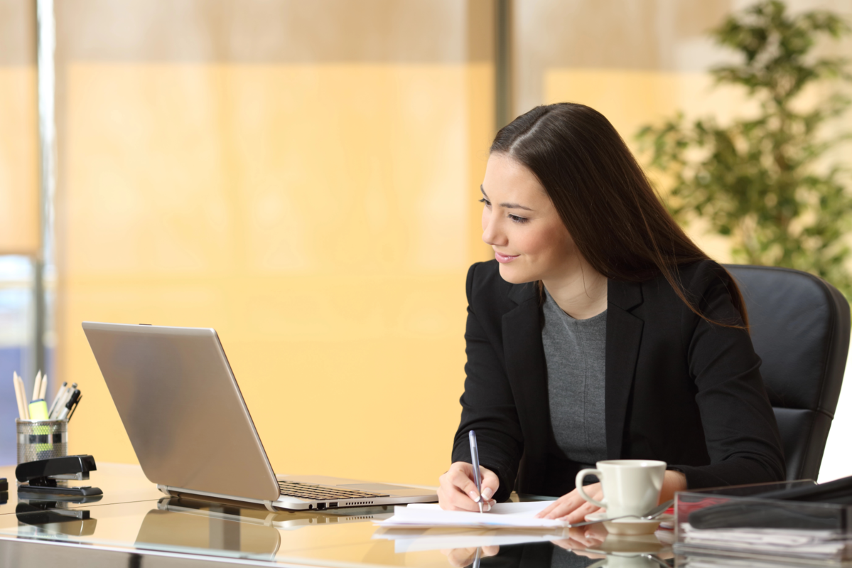 woman takes notes in an online training session with her laptop