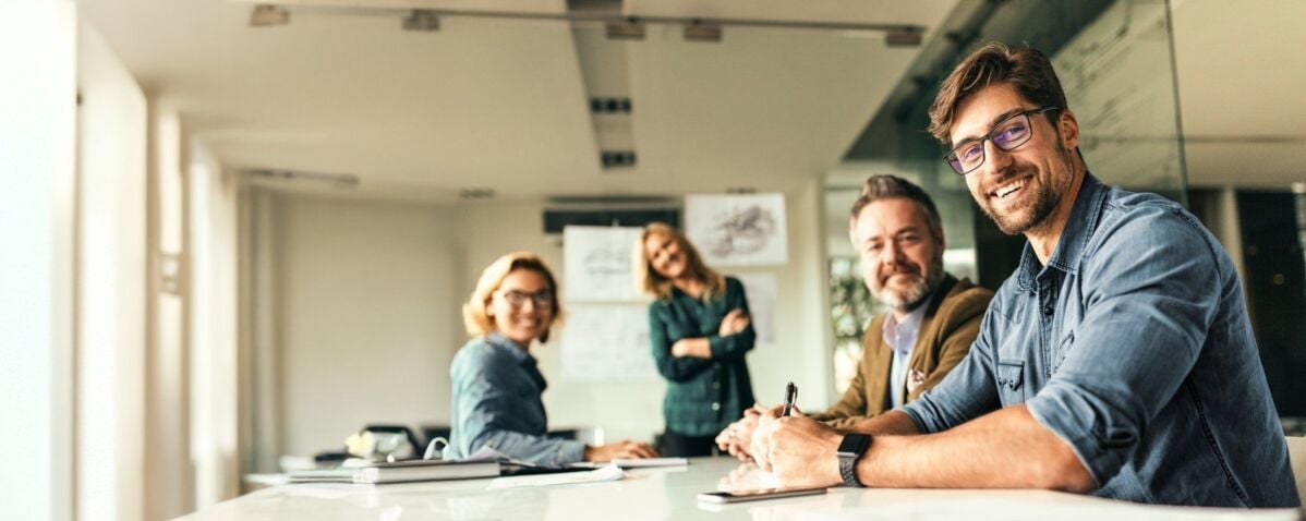 Happy group of businesspeople during presentation. Colleagues looking at camera and smiling.
