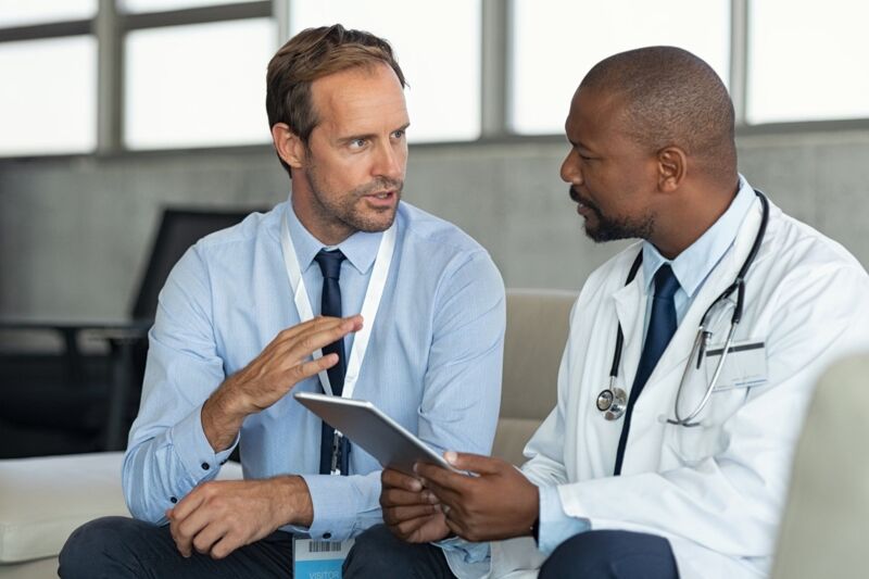 din-en-15224-certification-dqs-talk auditor with a doctor in a white coat with a tablet in his hand
