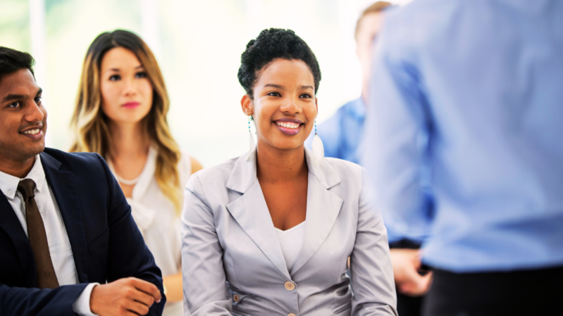 A diverse group of business professionals, representing various ethnic backgrounds, sits attentively