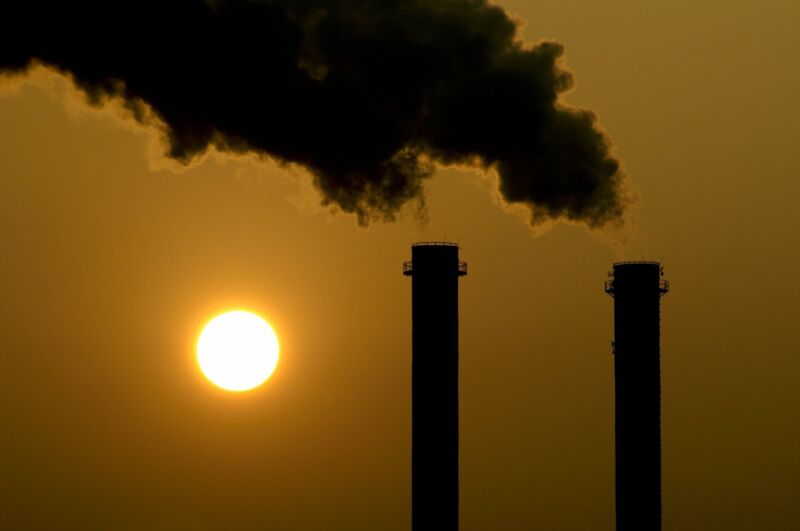 webinar-carbon footprint-dqs-two industrial chimneys with smoke in the sunset