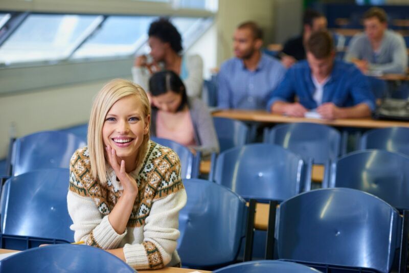 Loving college life. Portrait of a smiling college student sitting in a busy lecture hall