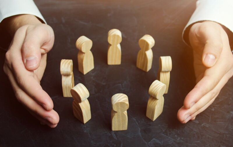 sa8000-certification-dqs-small wooden figures are placed in a circle and two hands symbolically hold