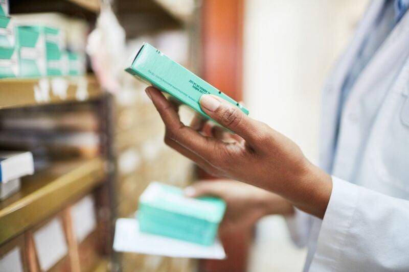 Close up of female pharmacist looking for medicines in the rack. Chemist searching the medicines at 