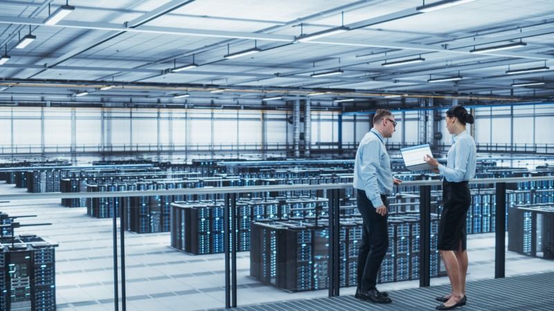 Man and a woman with a laptop in a server room